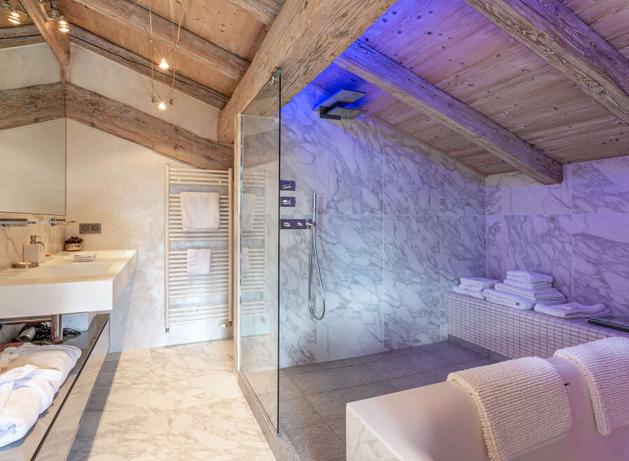 Luxurious bathroom with marble finishes and a spacious glass-enclosed shower.