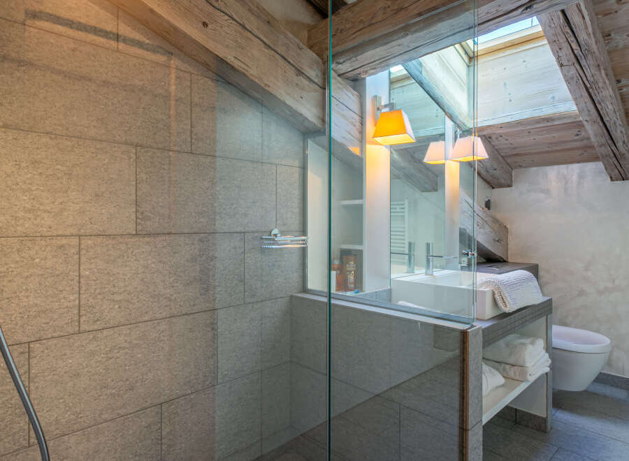 This luxurious bathroom boasts a spacious shower with modern fixtures and sleek gray tile.