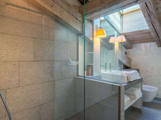 This luxurious bathroom boasts a spacious shower with modern fixtures and sleek gray tile.