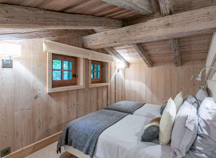 Cozy chalet bedroom with twin beds, featuring rustic wood beams and walls.