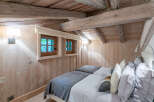 Cozy chalet bedroom with twin beds, featuring rustic wood beams and walls.