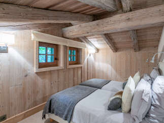 Cozy chalet bedroom with twin beds, featuring rustic wood beams and walls.