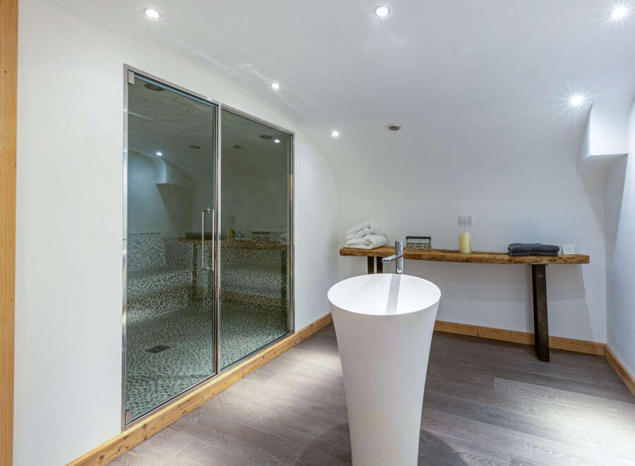 Luxurious spa-like bathroom with a modern free-standing sink and a glass-enclosed sauna.