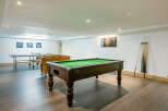 This stunning game room boasts a full-size pool table, table tennis, and foosball, perfect for entertaining guests of all ages.