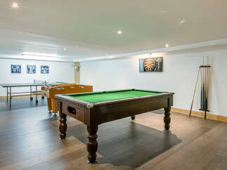 This stunning game room boasts a full-size pool table, table tennis, and foosball, perfect for entertaining guests of all ages.