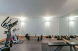 This home gym boasts a range of equipment, including an elliptical machine, exercise bike, barbell, dumbbells, and weight plates.
