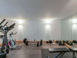 This home gym boasts a range of equipment, including an elliptical machine, exercise bike, barbell, dumbbells, and weight plates.