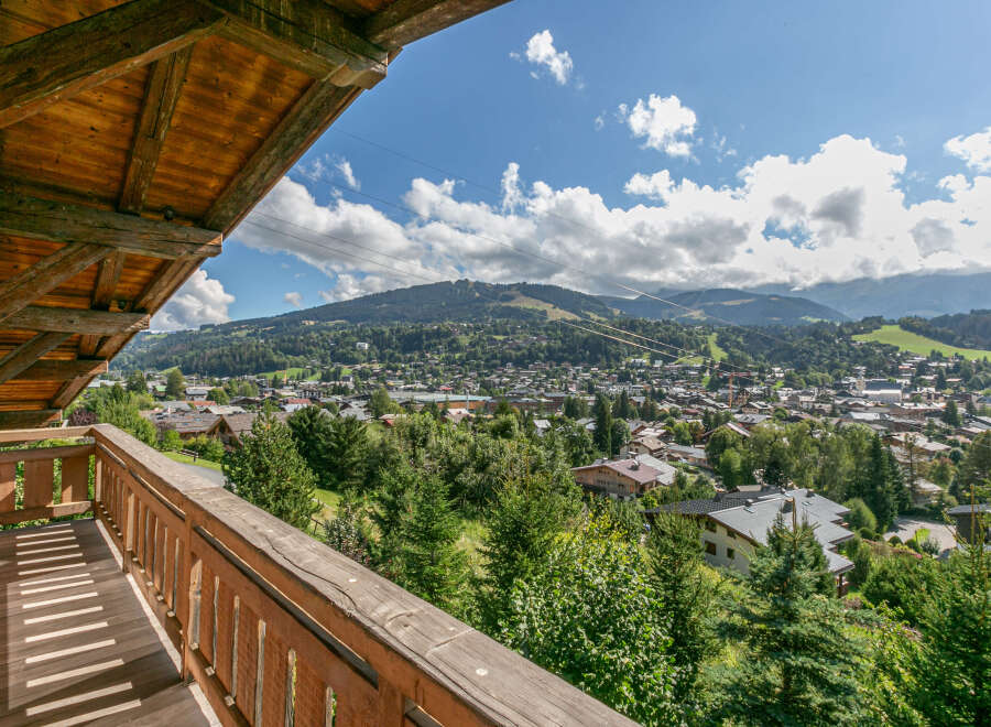 This stunning property boasts a spacious wooden balcony offering breathtaking panoramic views of the surrounding mountains and charming town below.