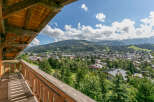 This stunning property boasts a spacious wooden balcony offering breathtaking panoramic views of the surrounding mountains and charming town below.