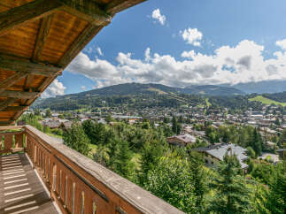 This stunning property boasts a spacious wooden balcony offering breathtaking panoramic views of the surrounding mountains and charming town below.