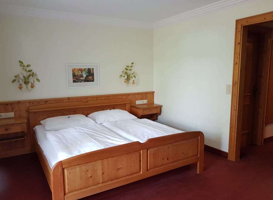 This cozy bedroom features a comfortable wooden bed with fresh white linens, perfect for a relaxing stay.