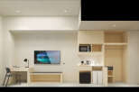 This modern hotel room boasts a minimalist design with built-in wooden cabinetry, including a workspace with a chair and a TV, and a kitchenette area with a microwave and kettle.