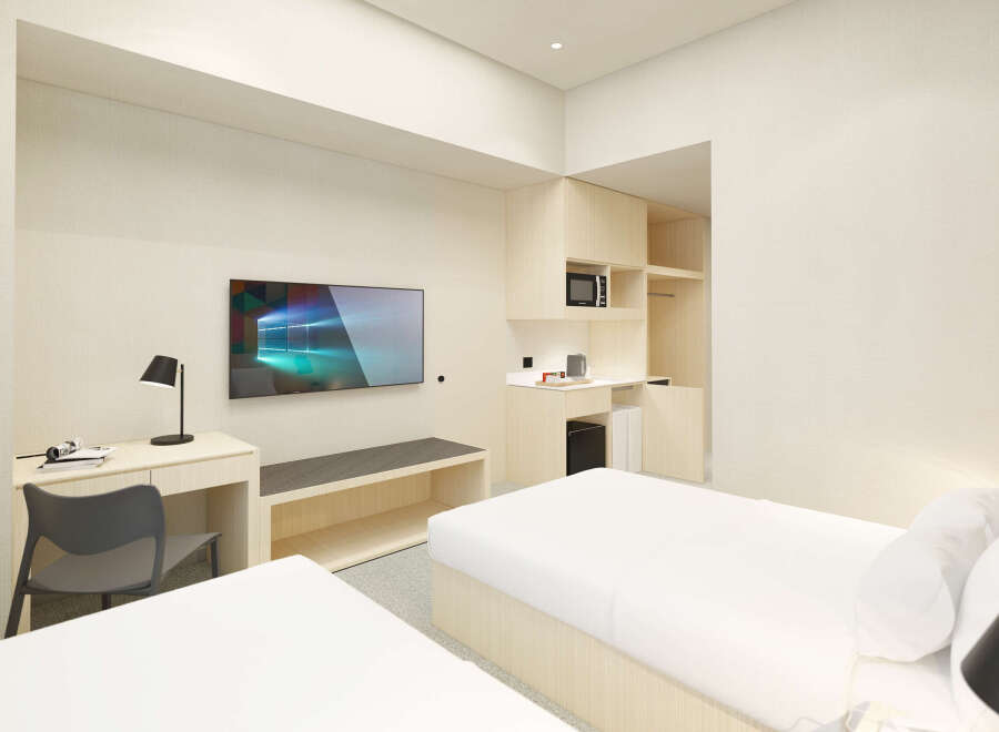 This modern hotel room features two twin beds with crisp white linens, a sleek wooden desk with a chair, and a flat-screen TV.