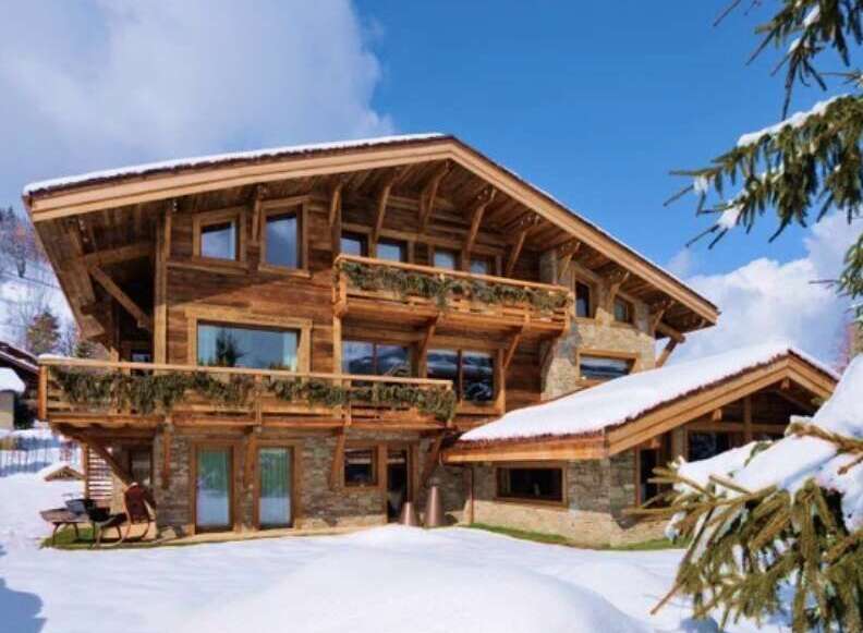 Luxury chalet in the snowy mountains, boasting stunning wooden architecture and multiple balconies.