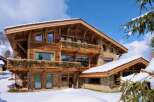 Luxury chalet in the snowy mountains, boasting stunning wooden architecture and multiple balconies.