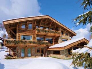 Luxury chalet in the snowy mountains, boasting stunning wooden architecture and multiple balconies.