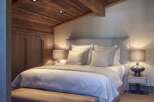 Luxurious chalet bedroom with wooden beamed ceiling and plush bedding.