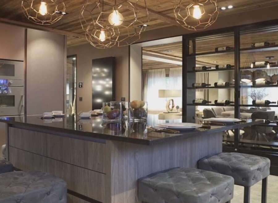 This luxurious kitchen boasts a stunning island with a dark countertop, complemented by plush gray stools.