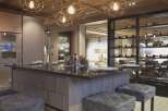 This luxurious kitchen boasts a stunning island with a dark countertop, complemented by plush gray stools.