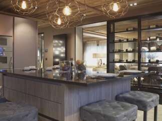This luxurious kitchen boasts a stunning island with a dark countertop, complemented by plush gray stools.