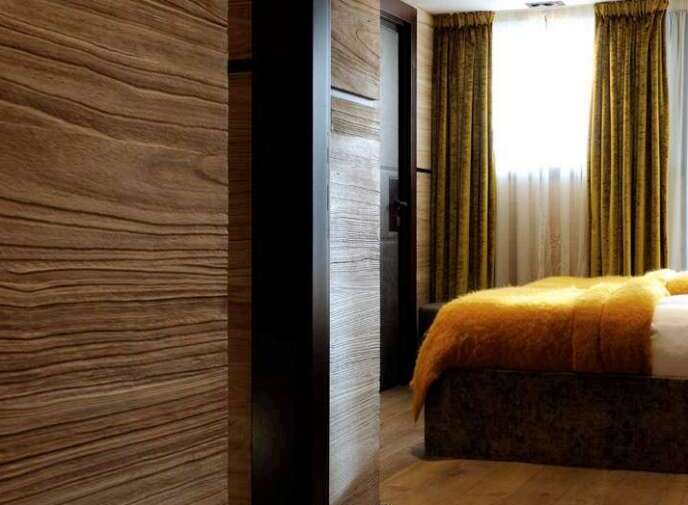 Luxurious bedroom with wood paneling and hardwood floors.