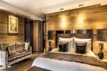 Luxurious chalet bedroom with wood paneling, plush furnishings, and a cozy atmosphere.
