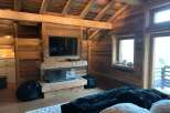 Rustic-chic bedroom with exposed wooden beams, a cozy fireplace, and plush bedding.