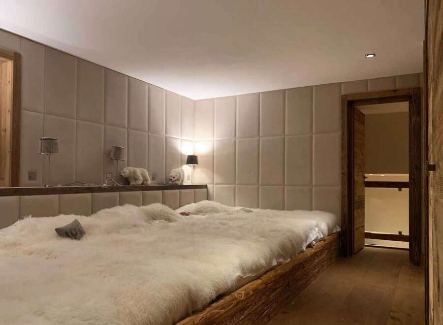 Luxurious chalet bedroom with plush sheepskin bedding and bespoke wall paneling.