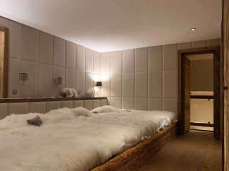 Luxurious chalet bedroom with plush sheepskin bedding and bespoke wall paneling.