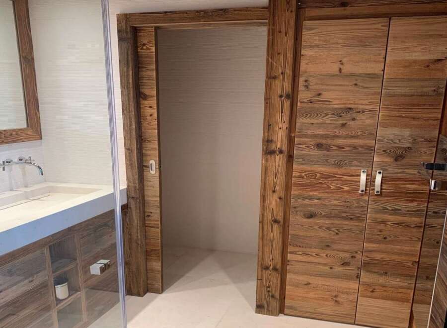 Luxury bathroom boasts a stunning reclaimed wood sliding door and double doors, adding rustic charm.