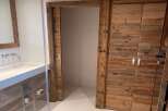 Luxury bathroom boasts a stunning reclaimed wood sliding door and double doors, adding rustic charm.