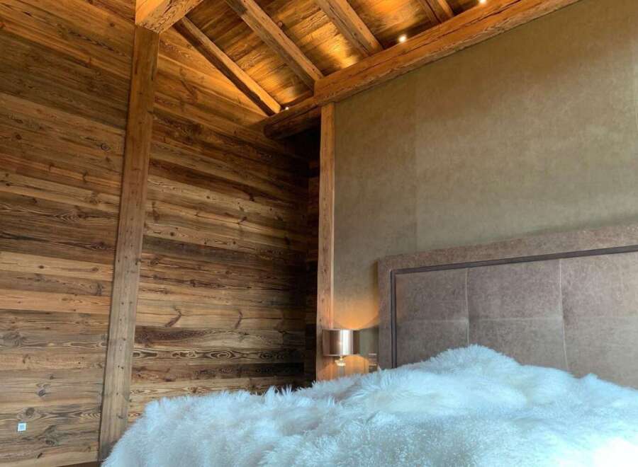 Luxurious chalet bedroom with reclaimed wood walls and beamed ceiling.