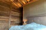 Luxurious chalet bedroom with reclaimed wood walls and beamed ceiling.