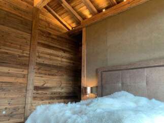 Luxurious chalet bedroom with reclaimed wood walls and beamed ceiling.