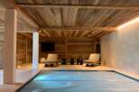Indulge in ultimate relaxation in this stunning indoor pool area, featuring a rustic wood-beamed ceiling and tranquil ambiance.