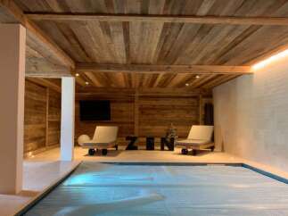Indulge in ultimate relaxation in this stunning indoor pool area, featuring a rustic wood-beamed ceiling and tranquil ambiance.