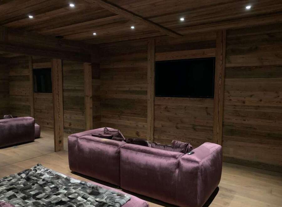 This luxurious home theater boasts stunning reclaimed wood walls and a coffered ceiling, creating a warm and inviting ambiance.