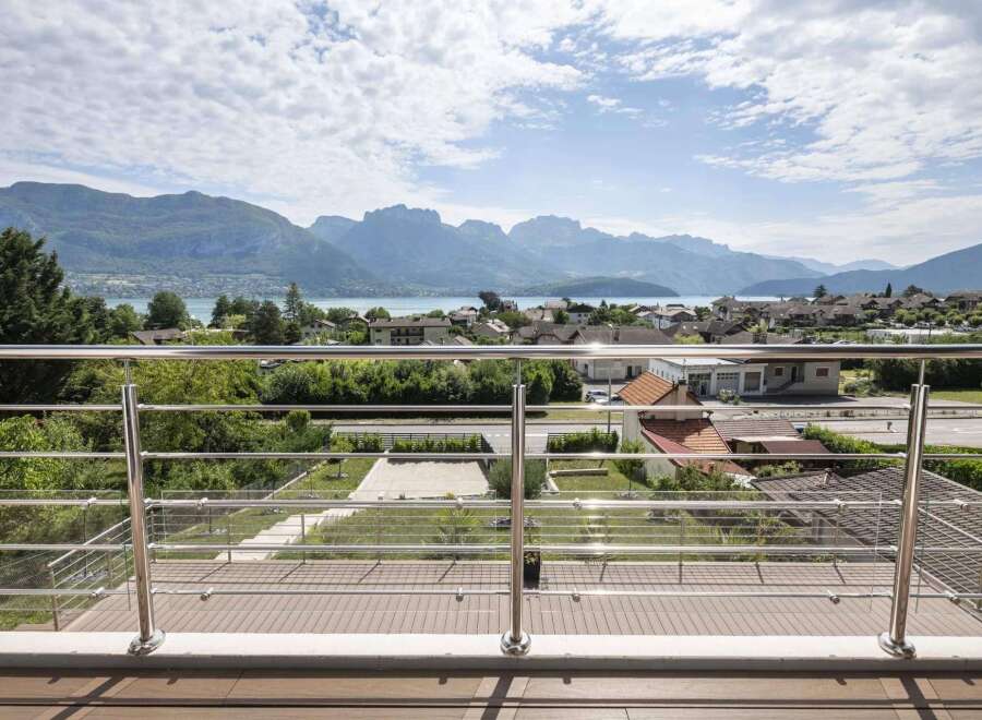 Luxury mountain view home with a spacious balcony featuring modern stainless steel railings and composite decking.