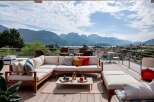 Luxury mountain view deck with sectional sofa and outdoor coffee table.
