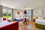 Discover a charming bedroom with a vibrant red bed frame, complemented by a cozy seating area.
