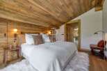 Experience luxury in this stunning bedroom featuring a rustic wooden ceiling and walls, creating a warm and inviting atmosphere.