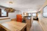 Discover the charm of this cozy property, featuring a rustic wooden interior and a unique driftwood chandelier.