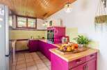 This charming kitchen boasts a unique design with vibrant pink cabinetry and warm wooden accents.
