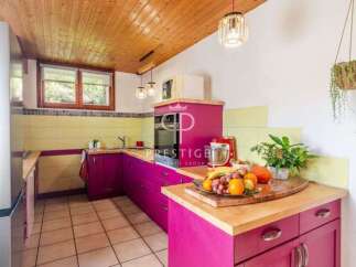 This charming kitchen boasts a unique design with vibrant pink cabinetry and warm wooden accents.