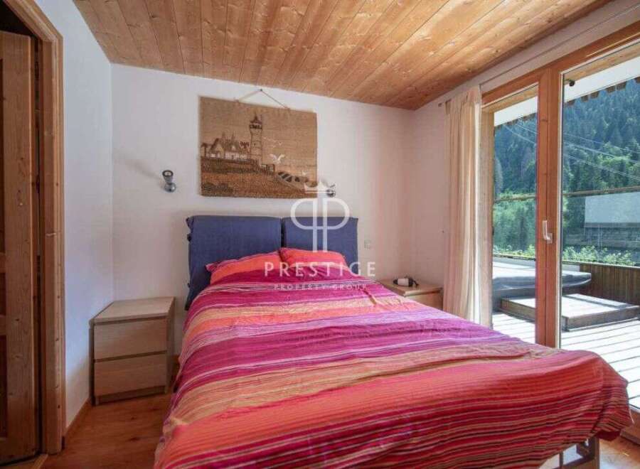 Cozy bedroom with a stunning view! This property features a wooden ceiling and a large window that opens to a balcony.
