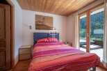 Cozy bedroom with a stunning view! This property features a wooden ceiling and a large window that opens to a balcony.
