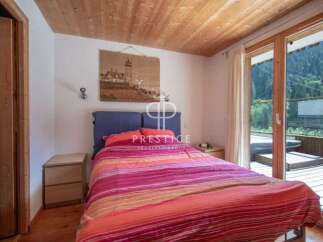 Cozy bedroom with a stunning view! This property features a wooden ceiling and a large window that opens to a balcony.