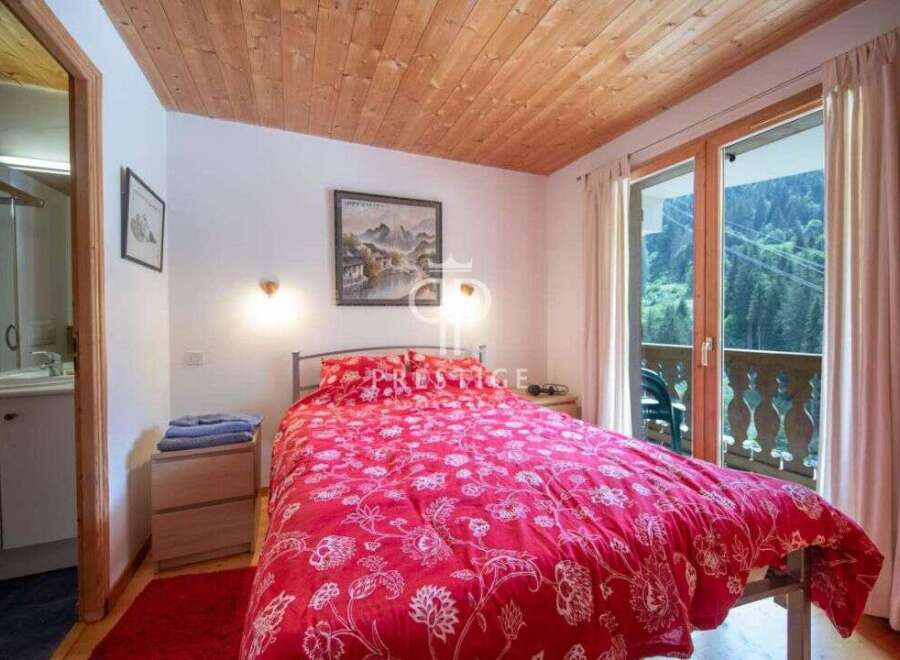 Cozy bedroom with a stunning view! This charming space features a comfortable bed with a vibrant red floral duvet, perfect for a relaxing stay.