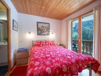 Cozy bedroom with a stunning view! This charming space features a comfortable bed with a vibrant red floral duvet, perfect for a relaxing stay.