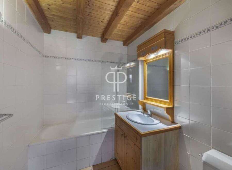 Discover this charming bathroom featuring a wooden ceiling and a stylish vanity.